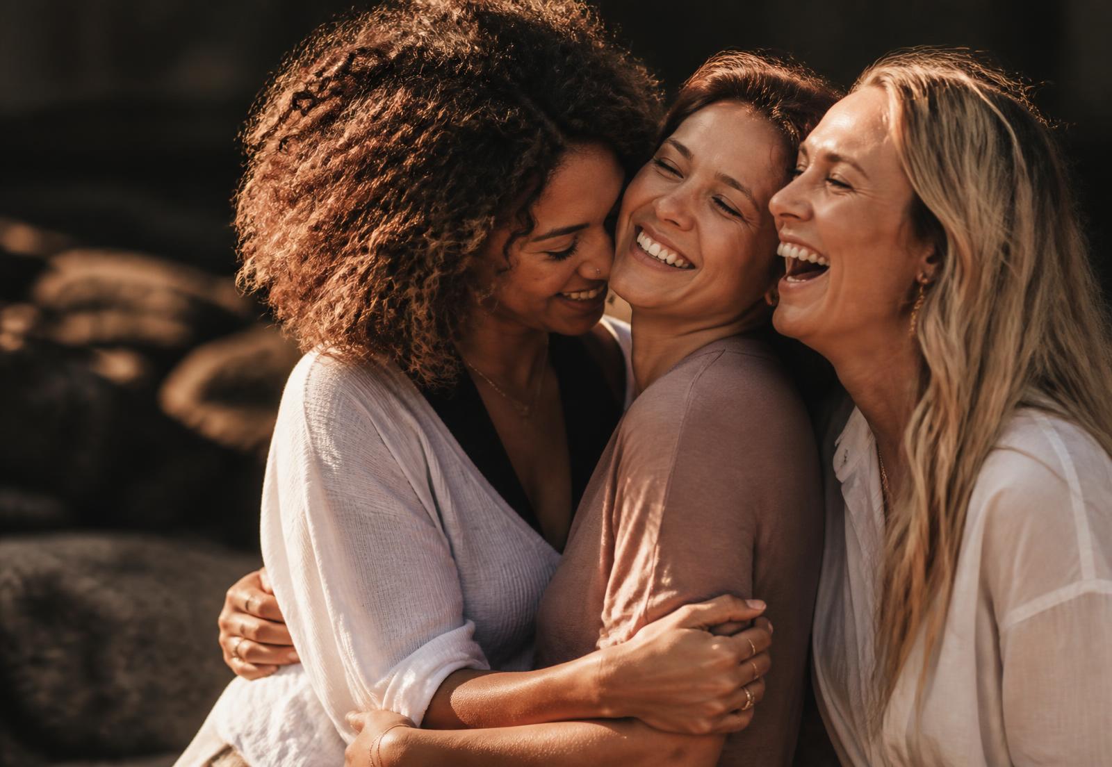Diverse women embracing and laughing together at golden hour